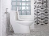 White toilet bowl and glass block partition wall inside of modern white bathroom
