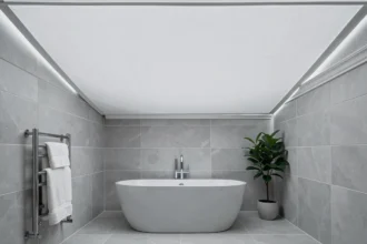 Plafond en toile tendue installé dans une salle de bain moderne avec baignoire îlot et carrelage gris